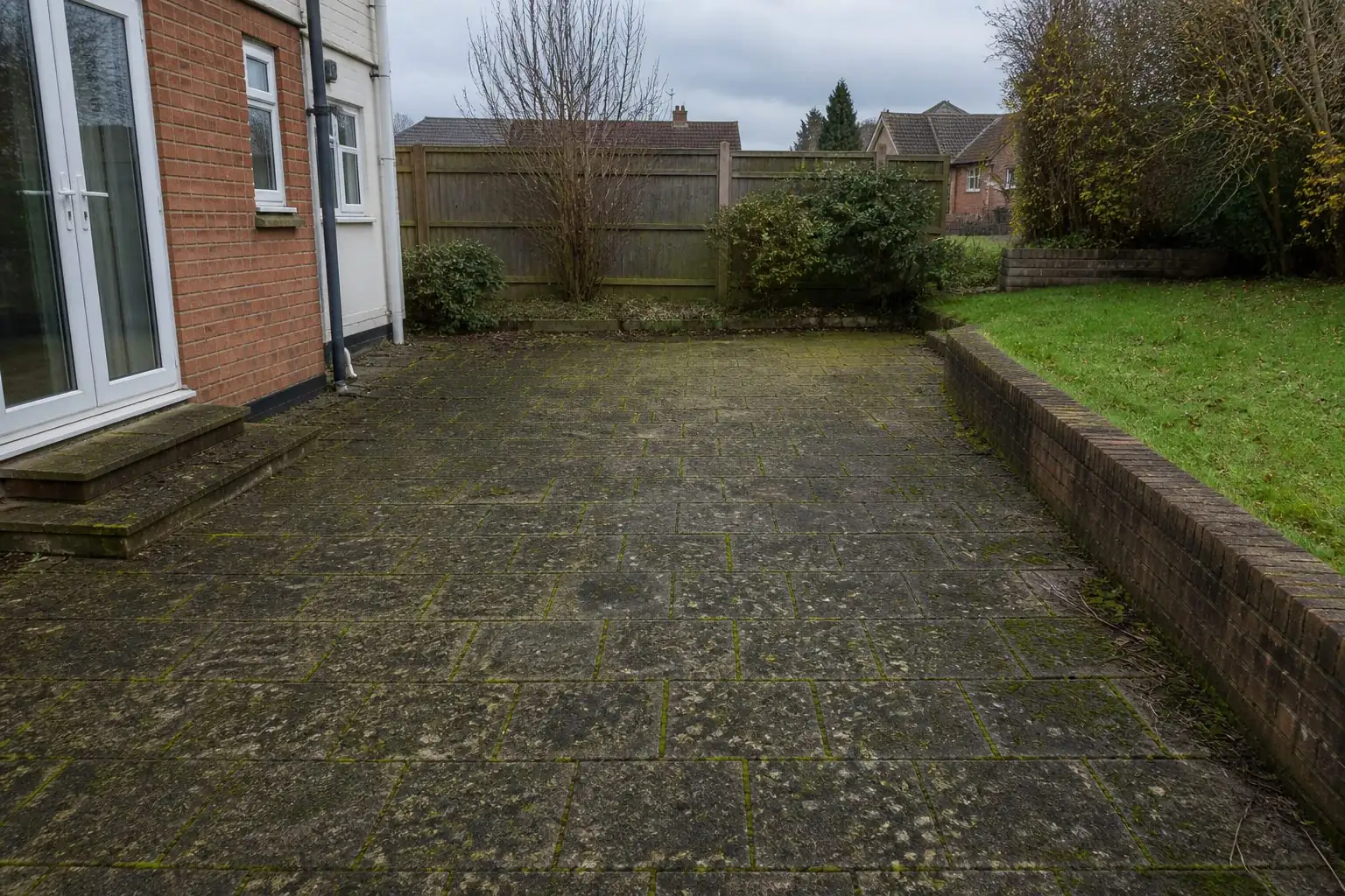 The same patio before cleaning, the slabs green with moss and algae