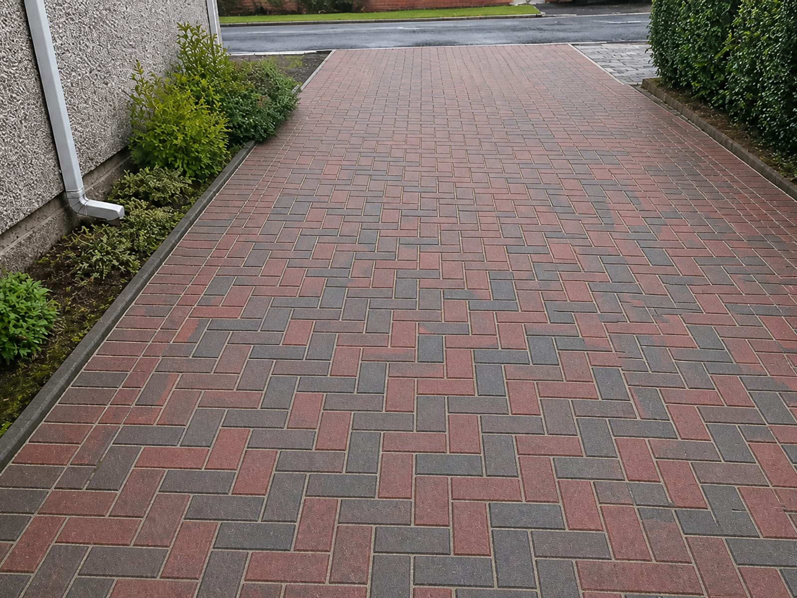 The same block paving driveway pressure washed back to its original red and charcoal, joints re-sanded