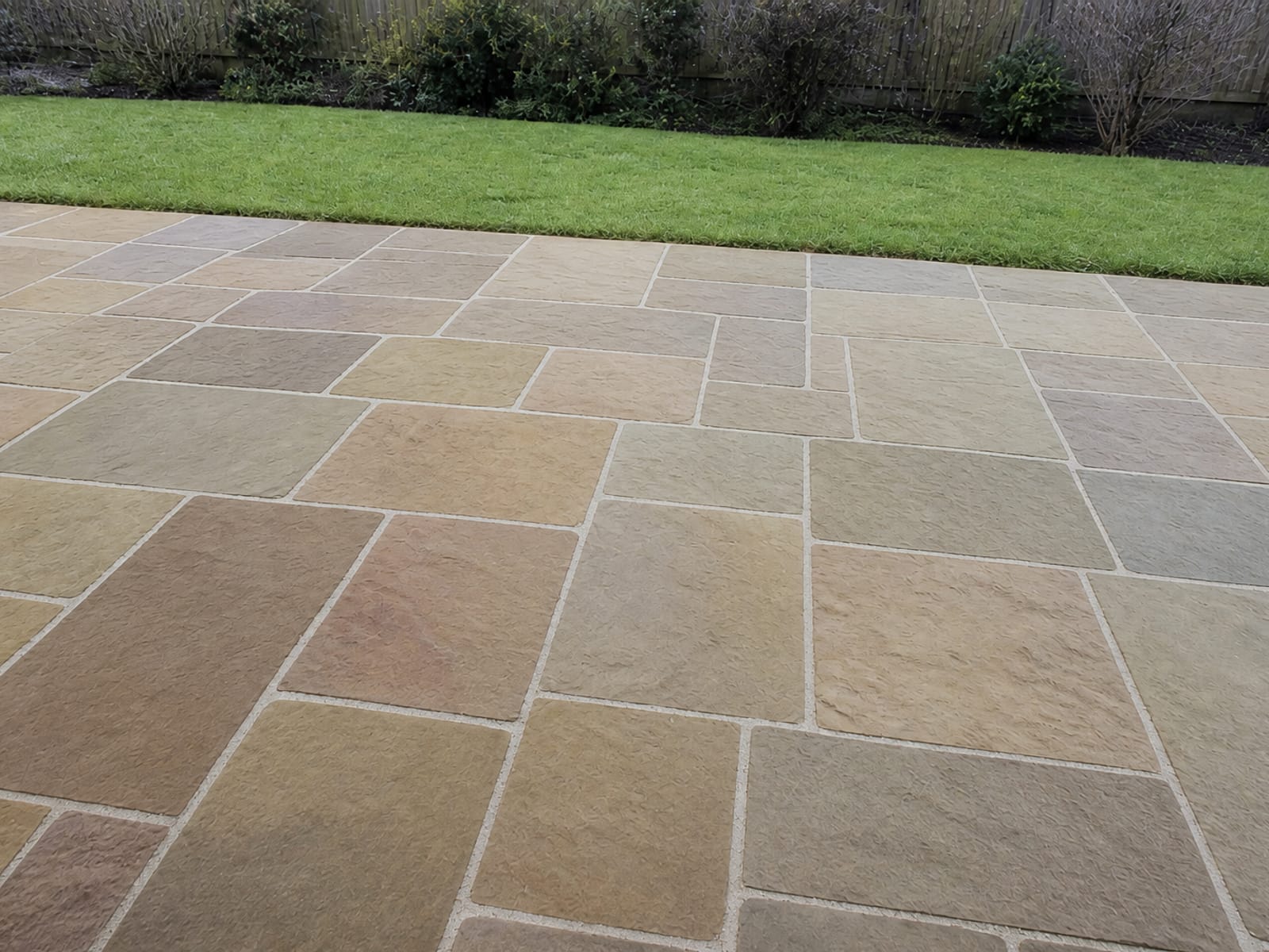 The same Indian sandstone patio cleaned back to its natural buff and grey tones